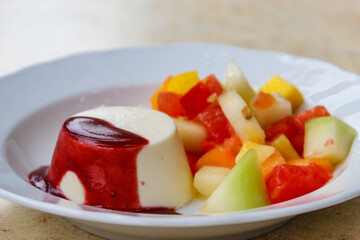 Traditional italian dessert vanilla panna cotta with sauce and fresh fruit salad