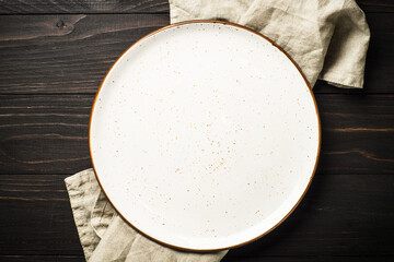 White craft plate at dark wooden table. Top view image with copy space.