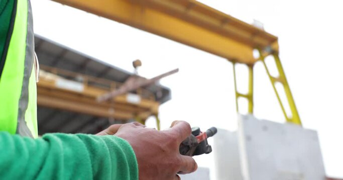 Closeup hand use remote control. Reinforced concrete structures. Man construction worker control large crane for placing precast concrete panels at Heavy Industry Manufacturing Factory