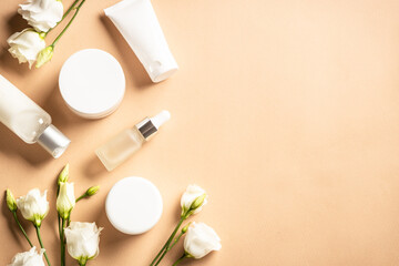 Obraz na płótnie Canvas Natural cosmetic products. Cream, serum, tonic with green leaves and flowers. Skin care concept. Flat lay image with copy space.
