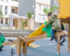 Two kids playing in a seesaw playground open air amusement park in the esplanade of a public...