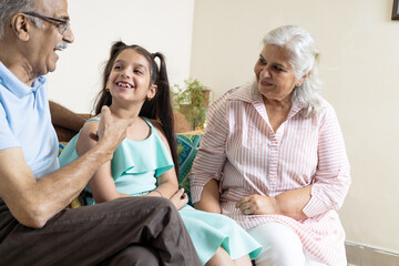 Grandparents and grand daughter having conversation together and looking each other ,