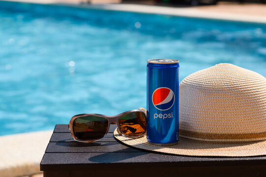 Anapa, Russia - July 20, 2023: A can of cold Pepsi with a hat and sunglasses on a table near the pool. Summer holiday concept.