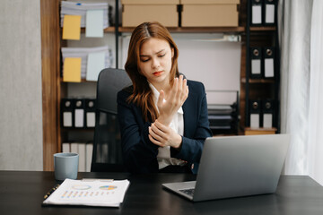 Overworked young Asian businesswoman office worker suffering from neck pain after had a long day at her office table. office syndrome concept