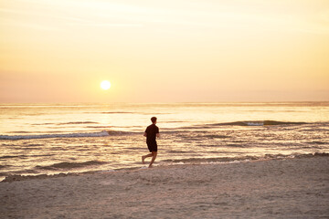 Silhouette of a Sportsman Running at Ocean Sunset. One person running against the sun.