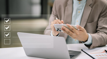 Fototapeta premium Businessman using smartphone to do online checklist survey, doing assessment online survey answer test questions Digital form.