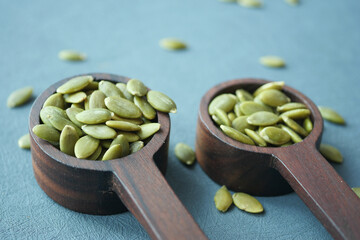Pumpkin seeds in wooden spoon on table 