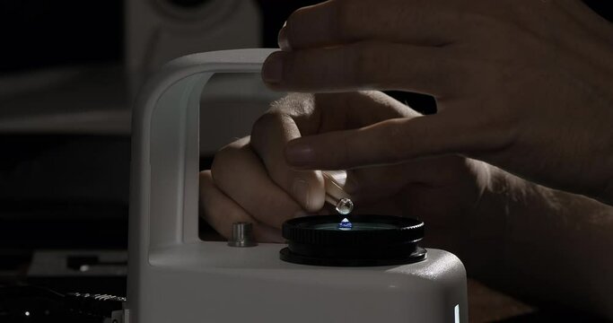 Gemologist checking sapphire gemstone to identify its grading and valuation. Gem quality control or inspecting in the gemmological laboratory.