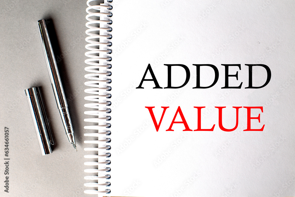 Poster added value text on a notebook with pen on grey background