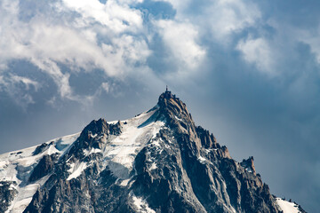 The Aiguille du Midi in the Mont Blanc Massif. The summit is 3,842 m high with the cable car, Telepherique de l'Aiguille du Midi stands at 3,777m - obrazy, fototapety, plakaty