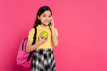 happy schoolgirl standing with backpack, holding apple and talking on smartphone, phone call