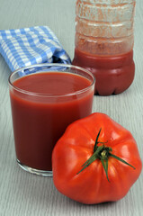 Verre de jus de tomate dans un verre avec une tomate et une bouteille de jus de tomate au second...