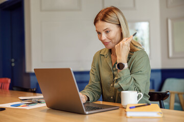 Focused woman entrepreneur working on laptop in modern coworking. Distance work concept