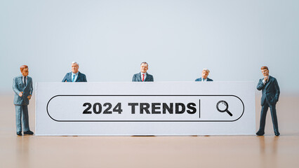 Miniature figure businessmen standing with white board and 2024 trends wording for business...