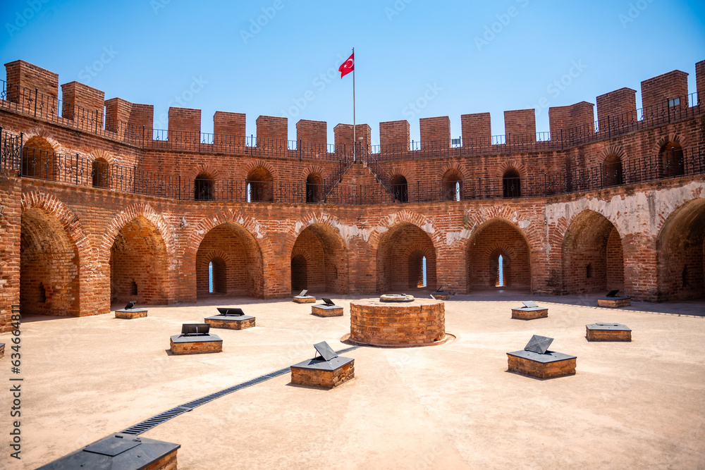 Poster view of alanya red tower in antalya with orenge bricks, on bright blue sky background.