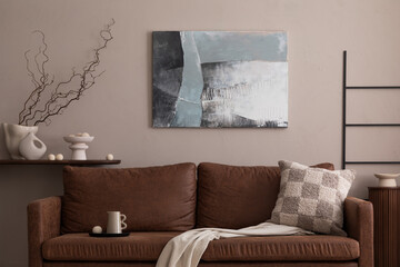 Minimalist composition of living room interior with mock up poster frame, brown sofa, patterned pillow, black ladder, wooden consola, beige wall and personal accessories. Home decor. Template.