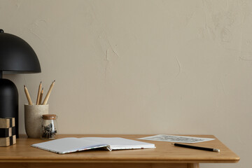 Minimalist composition of simple office interior with copy space, wooden desk, books, sculpture, cup with pencils, brown wall and personal accessories. Home decor. Template.