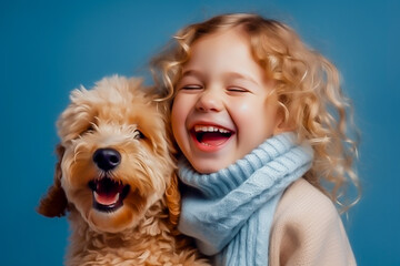 a happy little girl with curly blonde hair in a blue sweater, hugs a fluffy dog and laughs. Winter concept