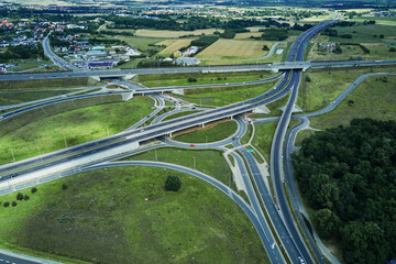 Fototapeta premium Aerial view of roundabout intersection with driving cars. Car traffic on highway with junction in Wroclaw, Poland. Rush hour in city