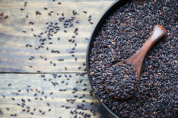 Bowl of Nerone rice, organic forbidden black, in a black bowl with wooden spoon. Selective focus with blurred background. Table top flatlay view.