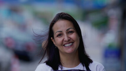 Happy Brazilian woman portrait face close-up standing in street looking at camera smiling. Authentic real life people