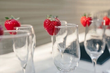 Empty glasses for champagne or cocktails decorated with ripe strawberries. Preparing cocktails for a party. Fresh sweet strawberries decorate a cocktail glass