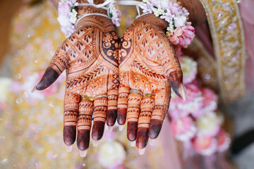 The hands of an Indian bride are decorated with henna designs and patterns in the traditional...