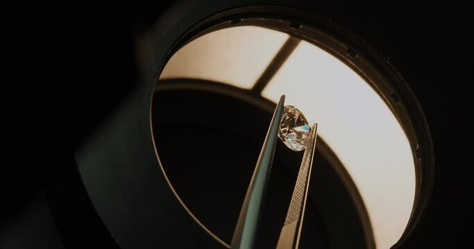 Diamond under microscope held by tweezers. Gemmological laboratory. Diamond or gem grading and valuation