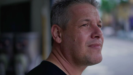 Man standing in street observing urban neighborhood. 40s middle aged male person looking at...