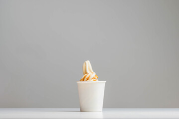 Caramel sundae ice cream placed on paper cup on white table with white background. Modern and fast dessert. Copy space.