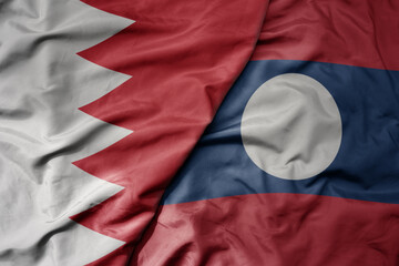 big waving realistic national colorful flag of bahrain and national flag of laos .