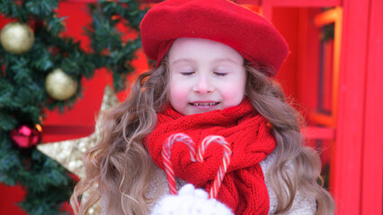 Portrait of young beautiful kid, child girl in Christmas decoration at winter snowy day near Christmas tree