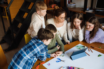 Female teacher using tablet during lesson with group of kids