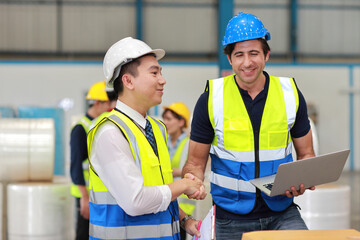 Group of technician engineer in protective uniform with hardhat standing and shaking hands celebrate successful together or completed deal commitment at industry warehouse manufacturing factory