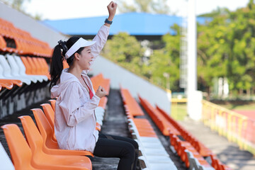 Portrait of happy and excited young female asian sport fan cheering and watching the match with her...