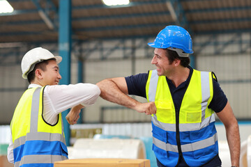 Two technician engineer man in protective uniform with hardhat standing and elbow bump celebrate...