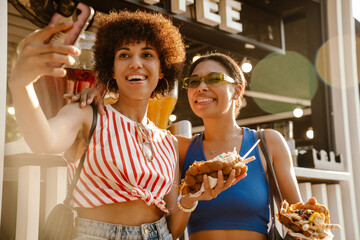 Two beautiful women taking selfie while standing outdoors near food court