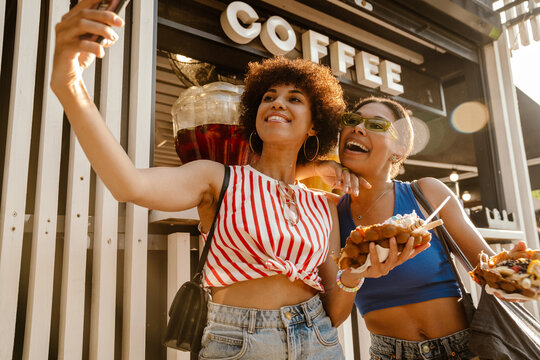 Two beautiful women taking selfie while standing outdoors near food court