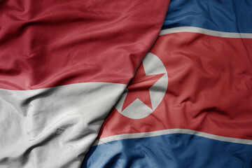 big waving realistic national colorful flag of indonesia and national flag of north korea .
