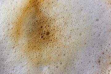 Top view of coffee foam texture. Cappuccino background with whipped foam and small bubbles.