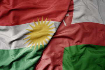 big waving realistic national colorful flag of kurdistan and national flag of oman .