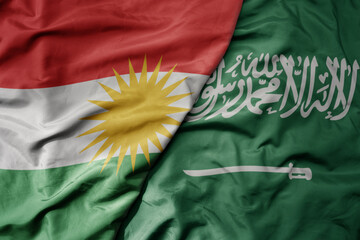 big waving realistic national colorful flag of kurdistan and national flag of saudi arabia .