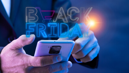 Businessman using smartphone for present glowing neon line of black friday sale shopping cart icon. Concept of great discount, suitable for black friday and anniversary.