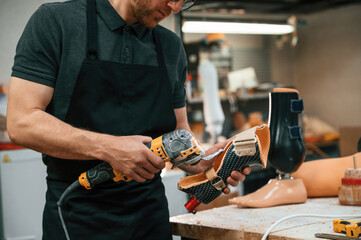 Cuts the material with drill. Technician working with prosthesis in modern laboratory