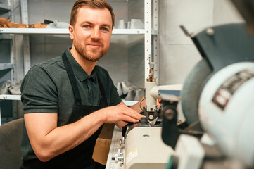 Working by sewing machine. Man in black shirt is indoors