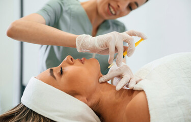 Obraz na płótnie Canvas A rejuvenating shot. Woman face getting facial care by beautician hands at spa salon