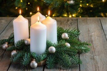 Advent wreath with four white candles, fir branches on wooden background. Sunday December. Traditional diy Christmas decoration, holidays background.