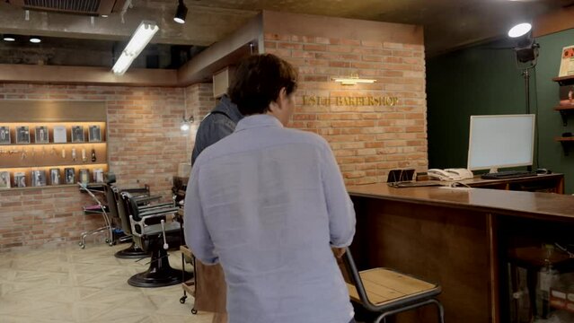 바버샵에서 손님과 스타일링에 관하여 대화를 나누는 헤어디자이너 