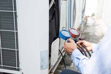 Mechanic air conditioner technician using manifold gauge checking refrigerant for filling home air conditioning maintenance outdoor compressor unit. - obrazy, fototapety, plakaty