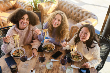 Cheerful multiracial female friends enjoying time in restaurant